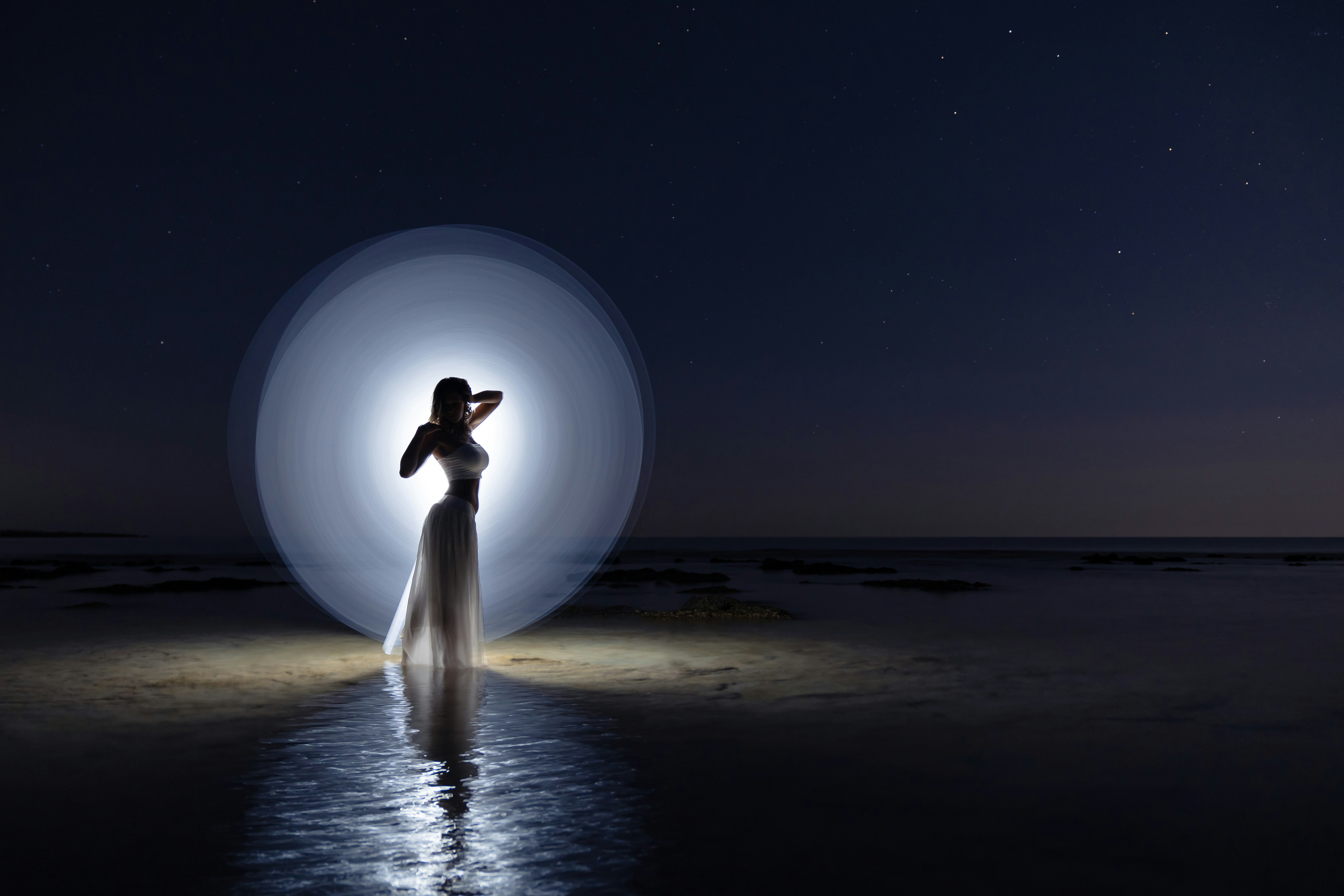 Une femme sur une plage dessinant un cercle avec de la lumière